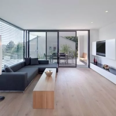Einblick-in-ein-Wohnzimmer-mit-dunkelgrauer-Couch-und-Terassentuer-mit-Schieberahmen-Insektenschutz